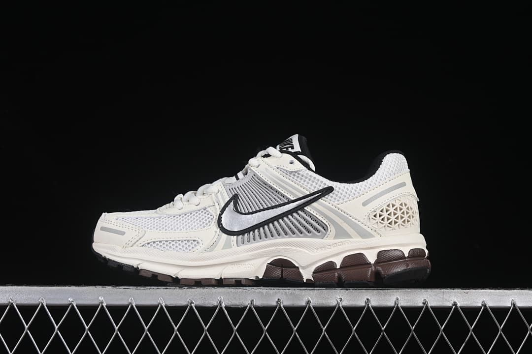 Side view of an off-white and grey Nike Zoom Vomero 5 sneaker with a silver Swoosh and dark outsole accents.