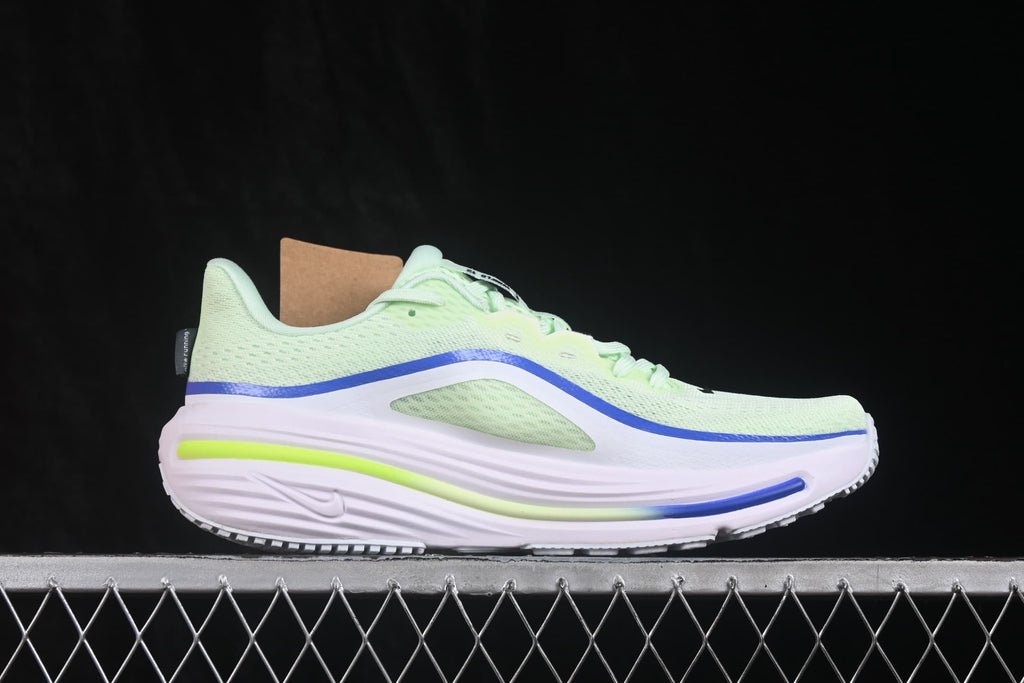 Side profile highlighting the perforated upper, blue trim, pale pink-white midsole and lime accent.