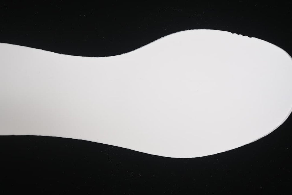 Plain white shoe insert shown against a dark background.