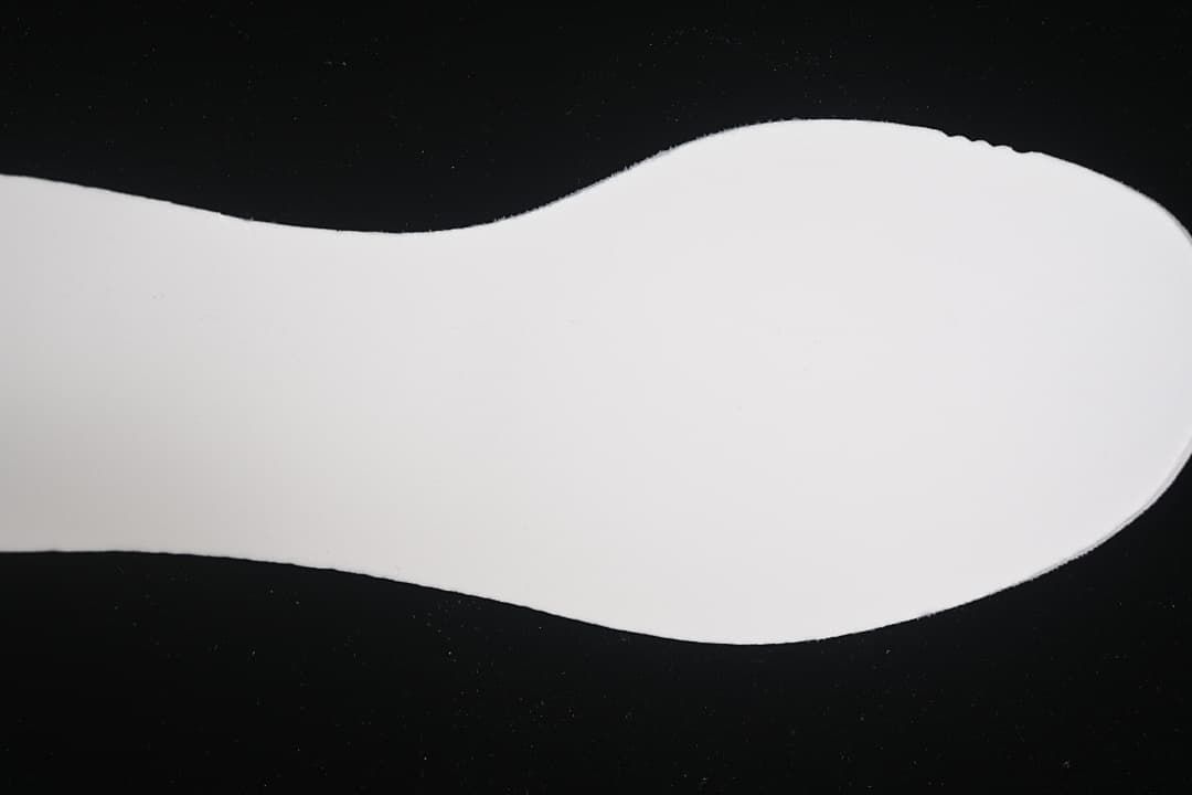 Plain white shoe insert shown against a dark background.