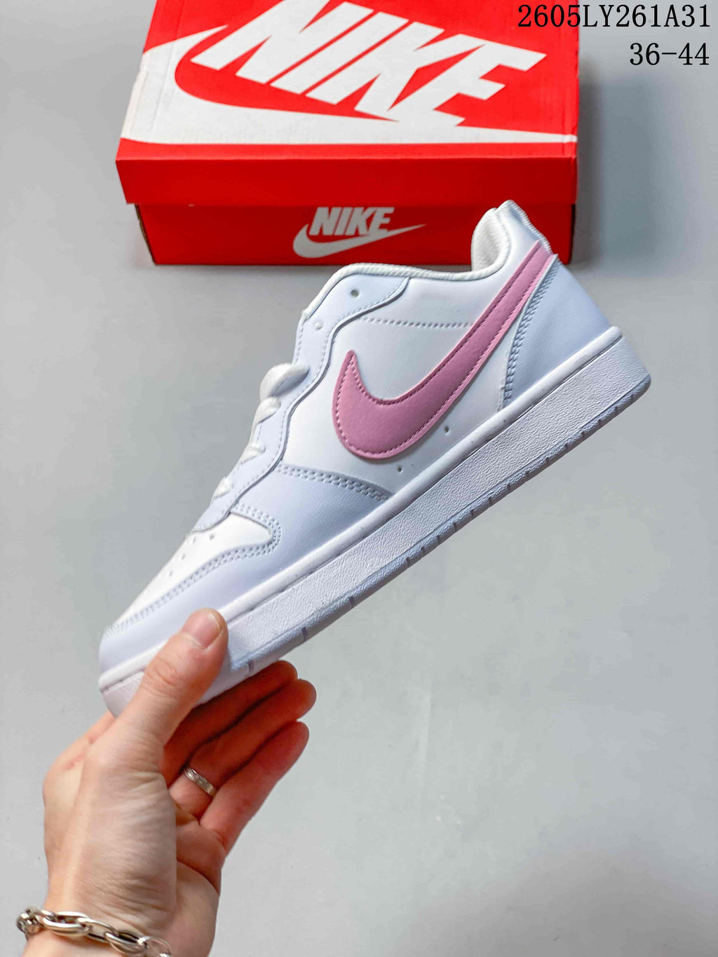 Side view of the white low-top sneaker with a pink Swoosh