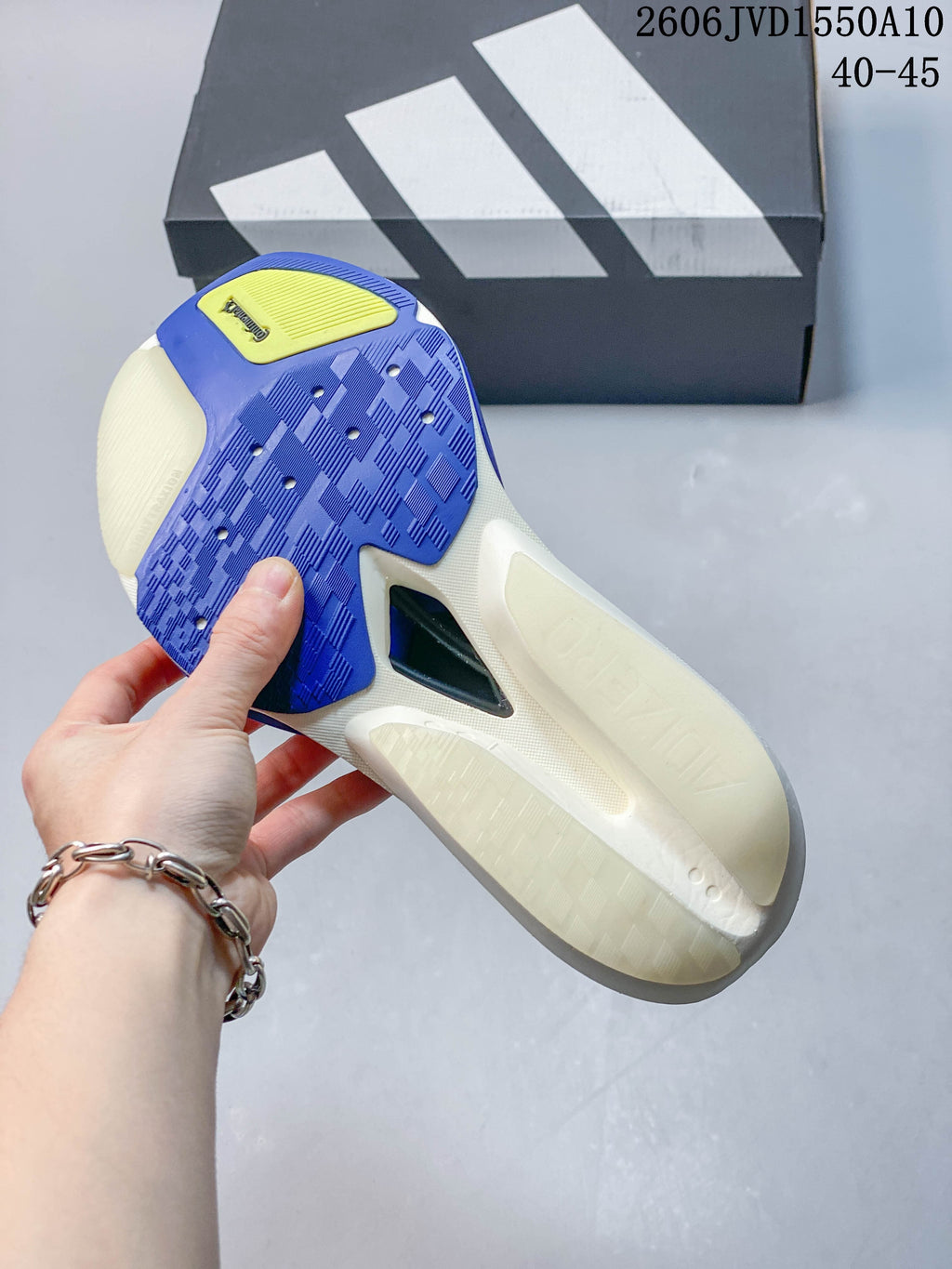 Outsole view of a white and blue running shoe showing the tread and central plate-like section.