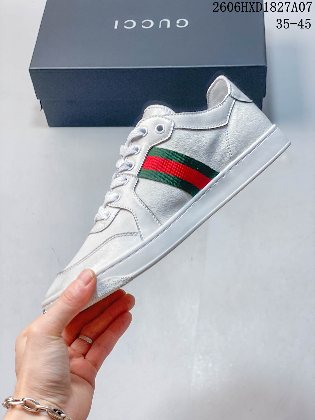 Side view of a white sneaker with green-and-red stripe and white sole.