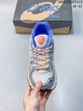 Top view of one ASICS sneaker showing the layered upper, contrasting laces, blue collar lining, and red tongue label.