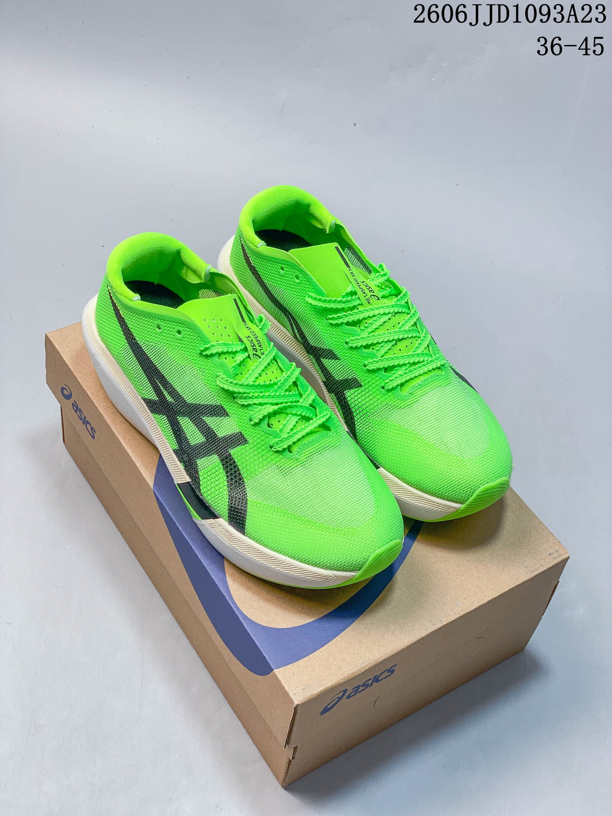 Bright green ASICS running shoes with dark side logos, photographed on a shoebox