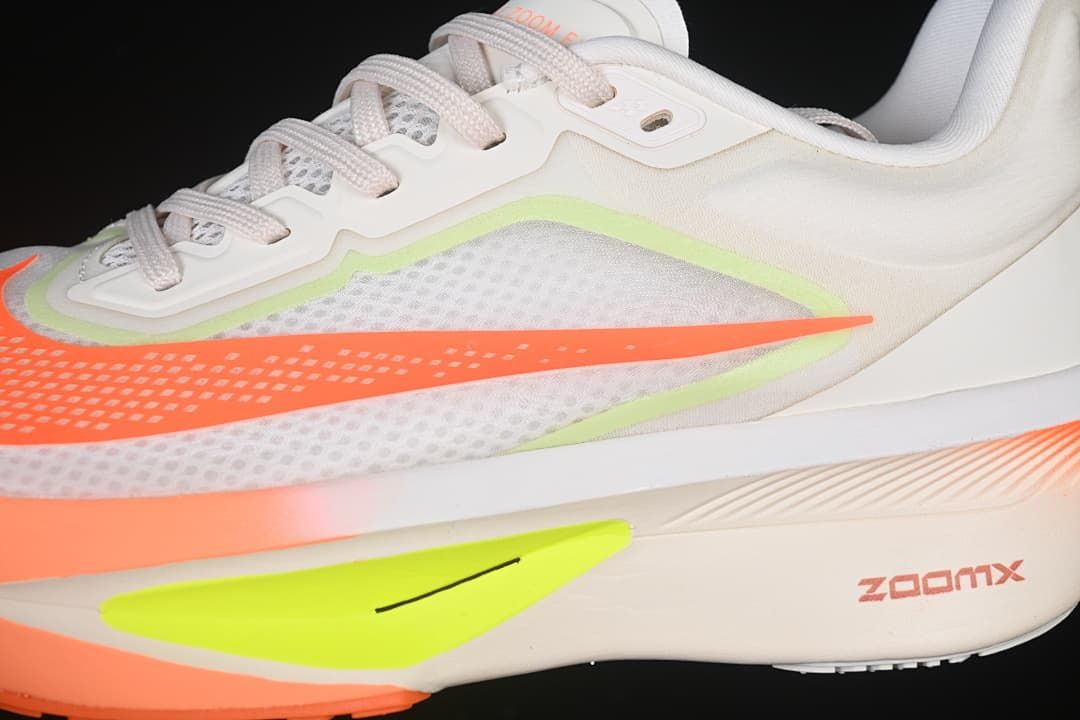 Close-up of the side mesh panels, orange logo, and neon yellow-green midsole detail.