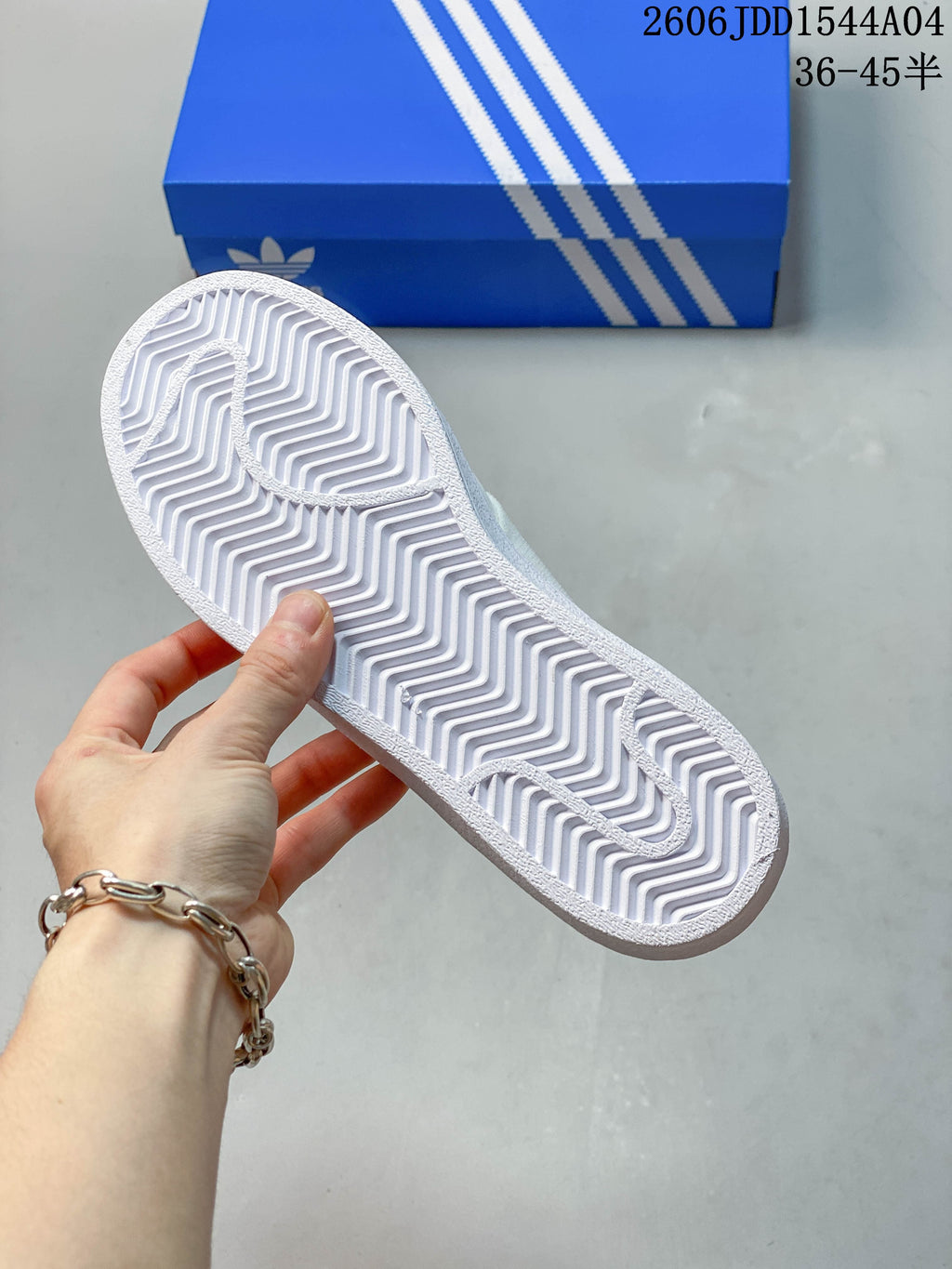 Underside of the white sneaker showing a patterned outsole.