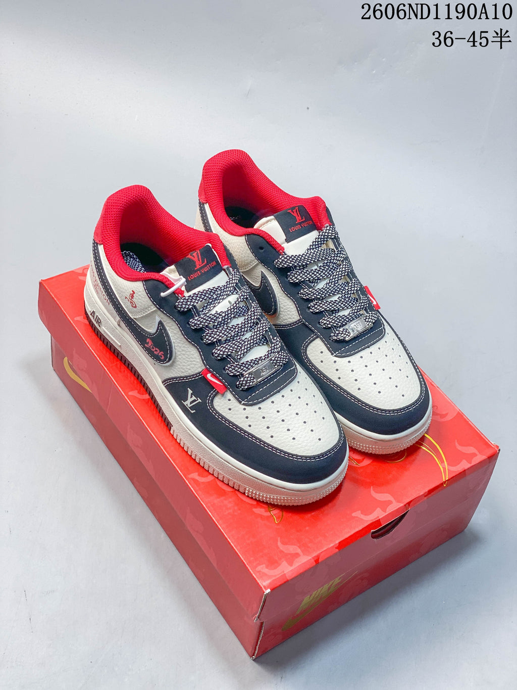 Pair of white, navy, and red low-top sneakers displayed on a red patterned shoebox