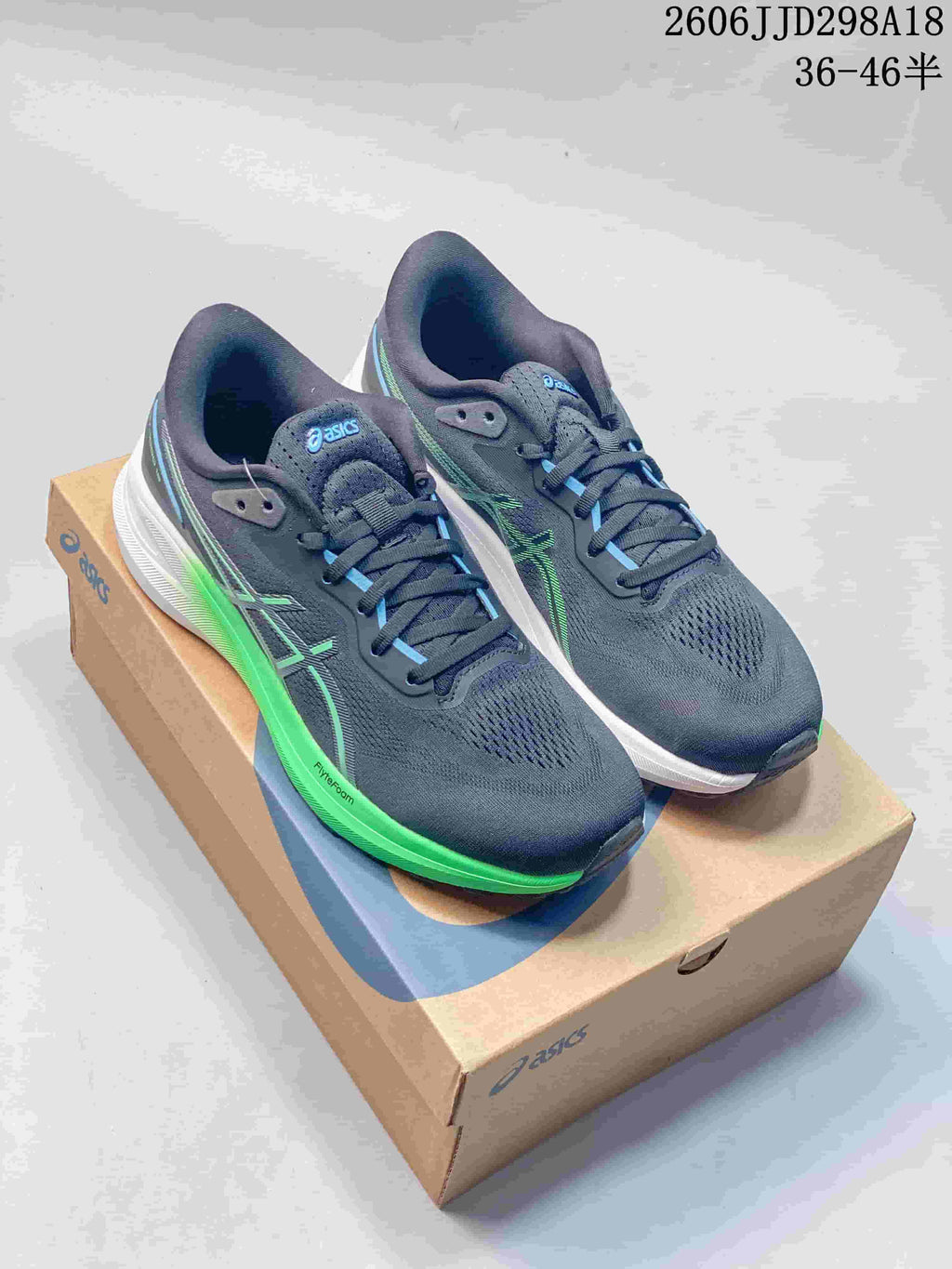 Pair of navy ASICS GT-1000 13 PARIS running shoes with green and blue accents, shown on a shoe box.