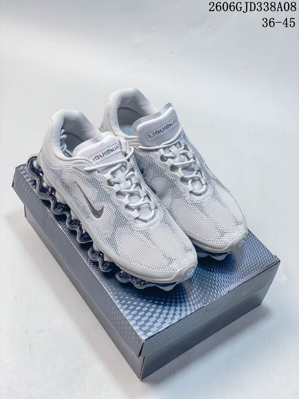 Pair of light grey Nike Air Liquid Max low-top sneakers on a patterned shoe box