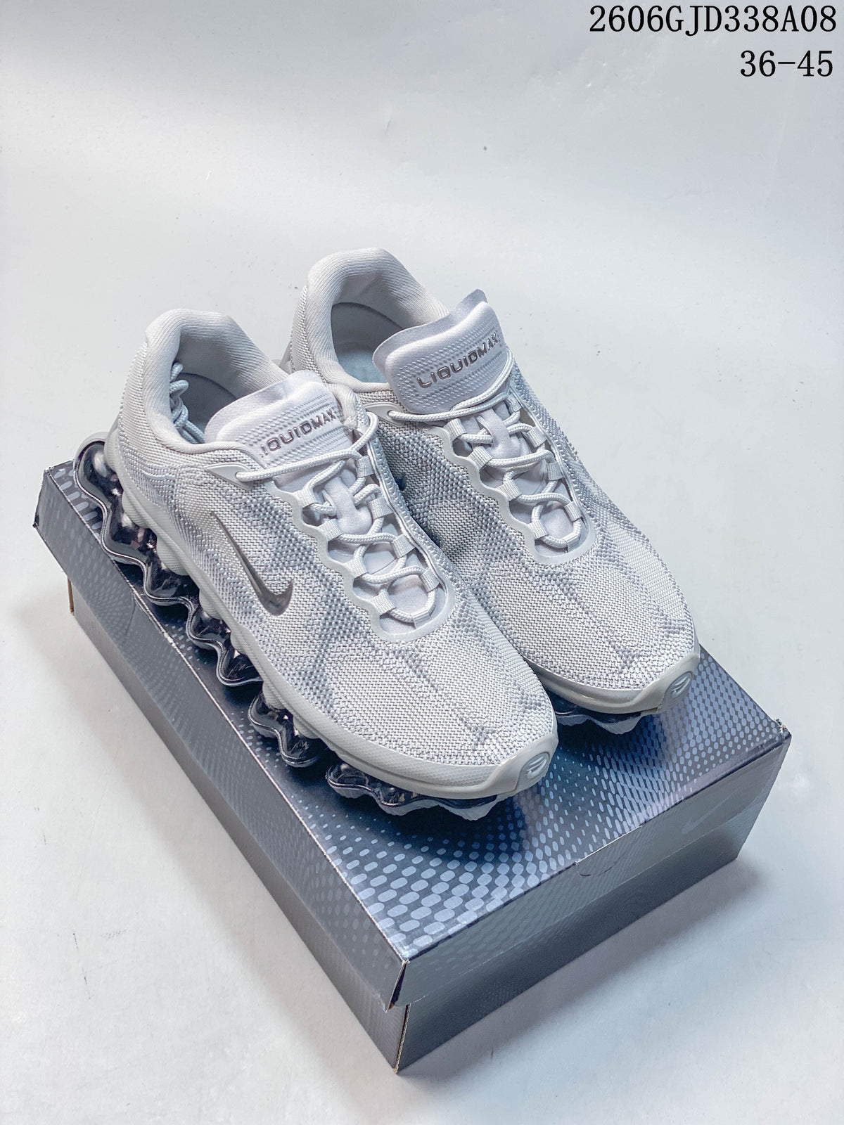 Pair of light grey Nike Air Liquid Max low-top sneakers on a patterned shoe box