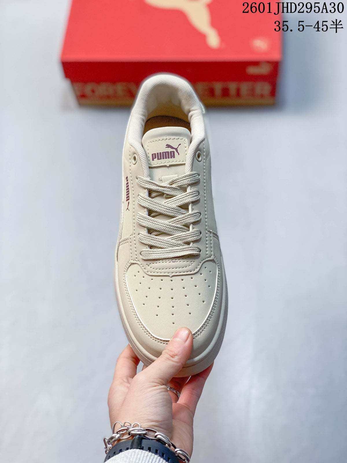 Top view of the perforated toe and lace-up front of a cream Puma sneaker