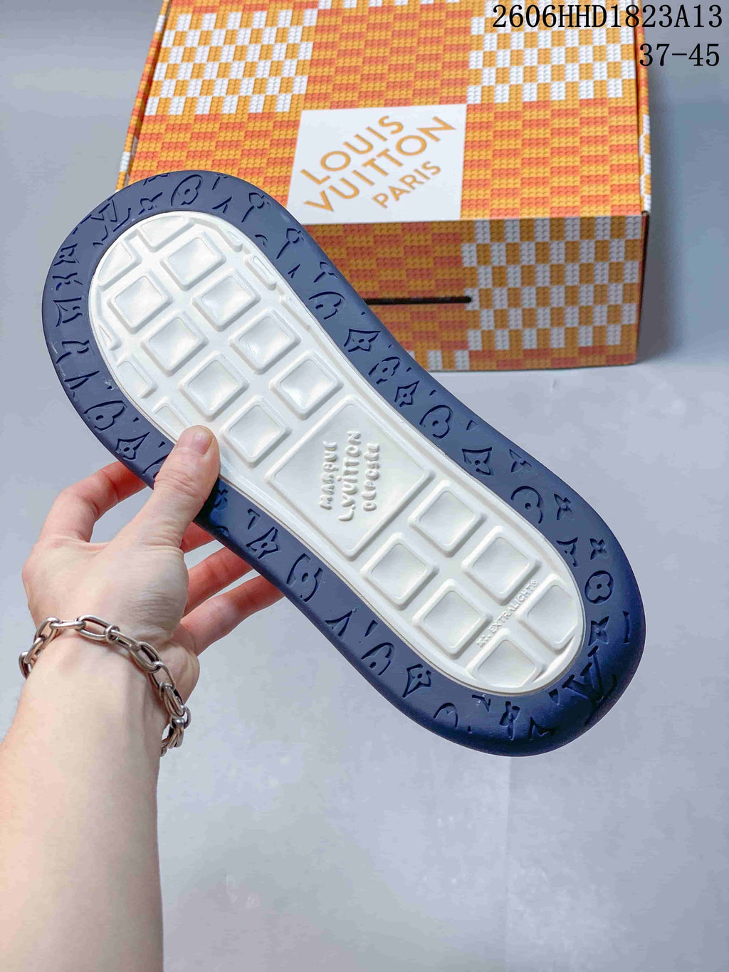 Underside of a sneaker showing a white tread center and dark blue patterned outsole.