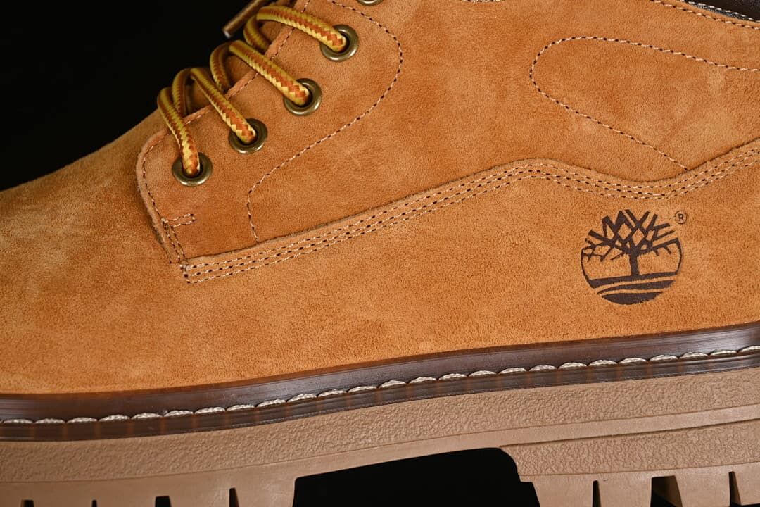 Close-up of the yellow-brown upper, laces, eyelets, stitching, and tree logo.