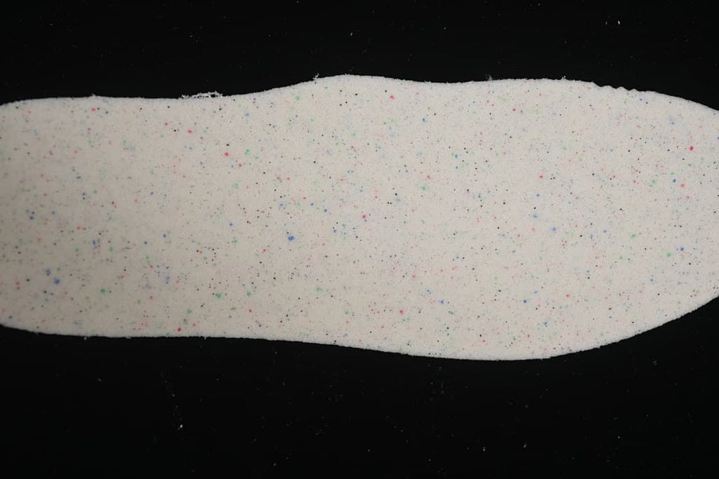 Removable insole showing a light-colored surface with multicolor speckles.