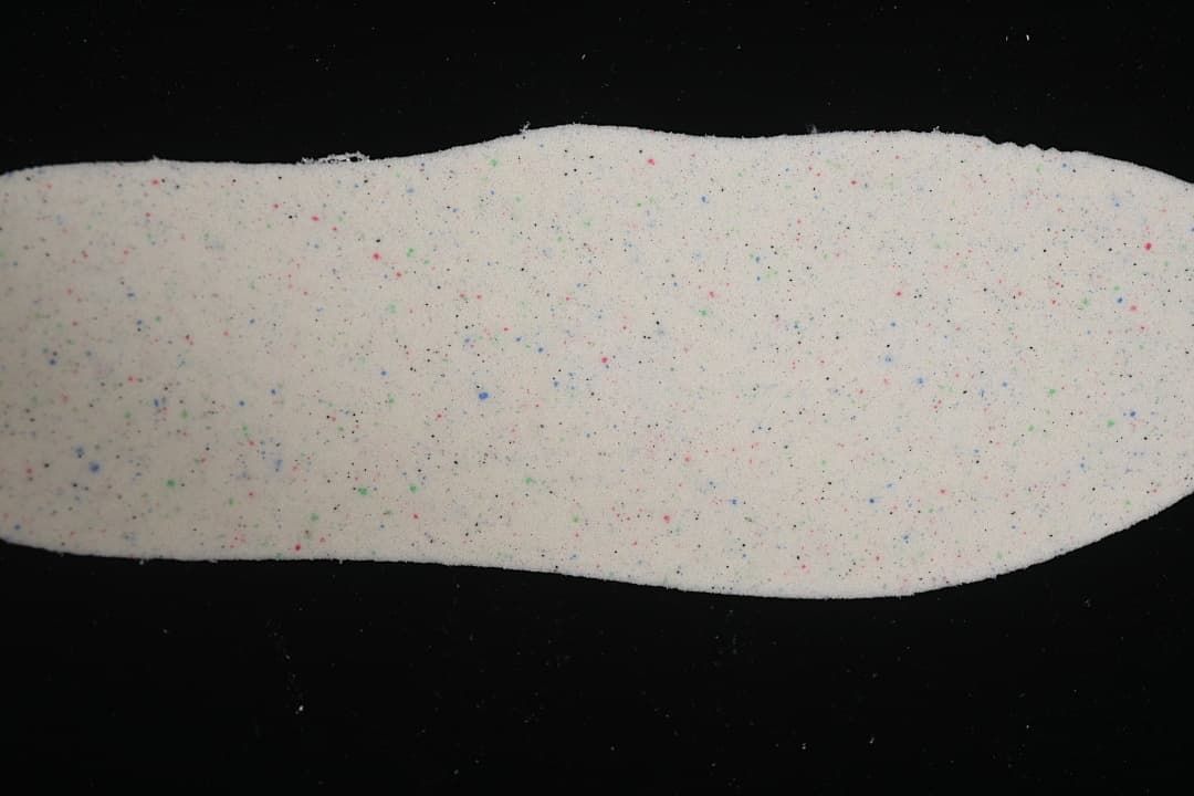 Removable insole showing a light-colored surface with multicolor speckles.