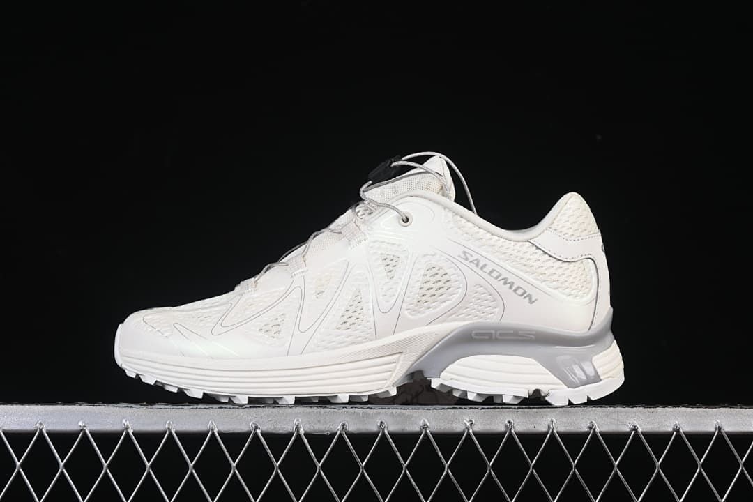 Side profile of light-colored Salomon XT-Whisper sneakers on a dark background