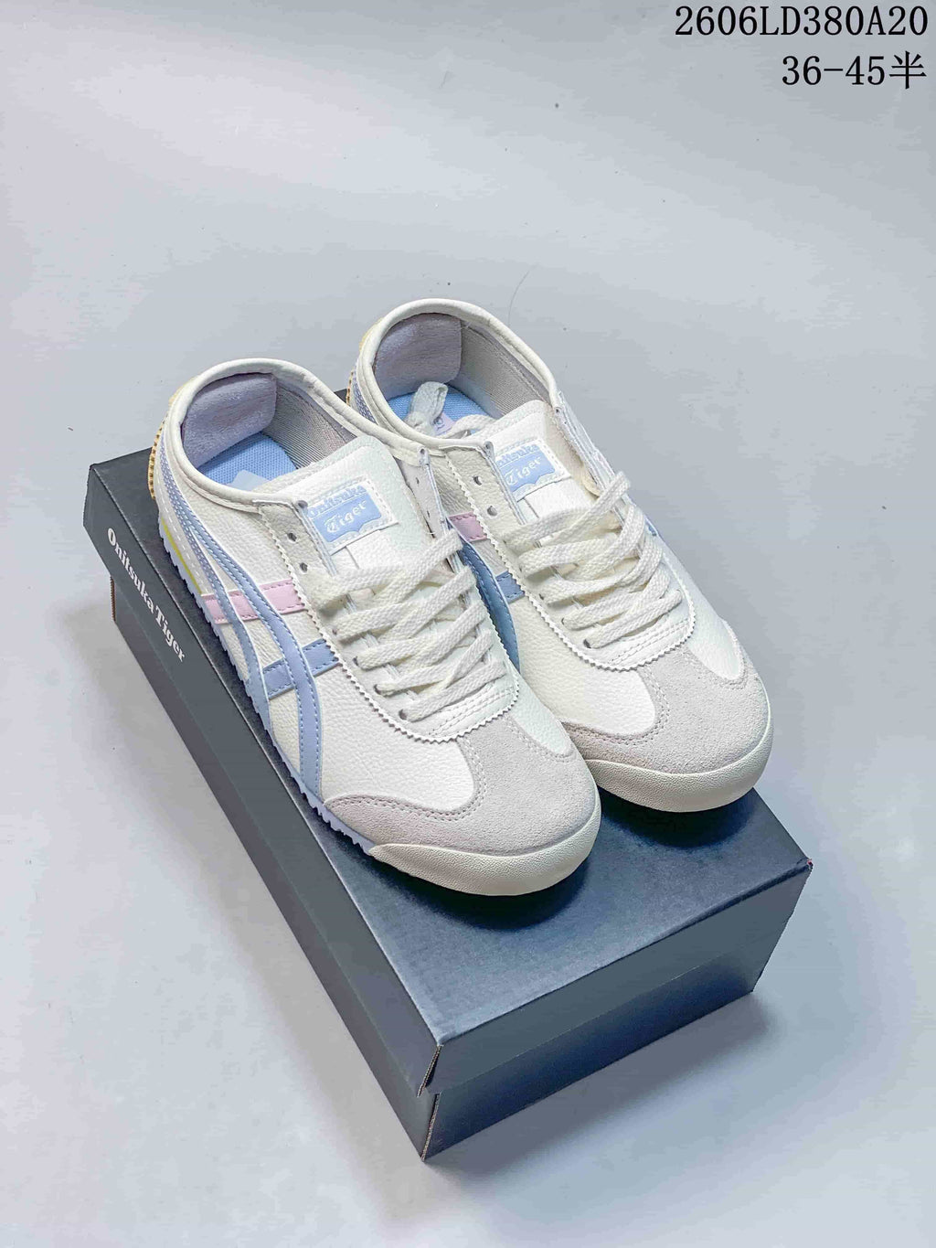 Pair of white low-top Onitsuka Tiger-style sneakers with pastel blue and pink side stripes, displayed on a shoe box.