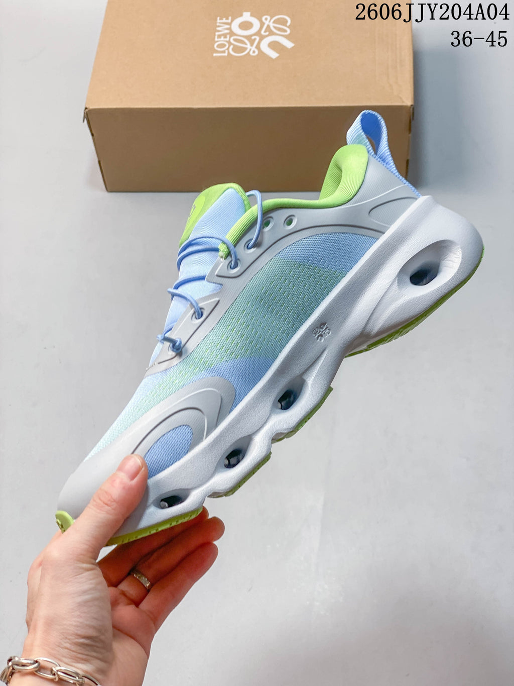 Side view of a light blue and pale green sneaker with elastic lacing and a sculpted white sole.