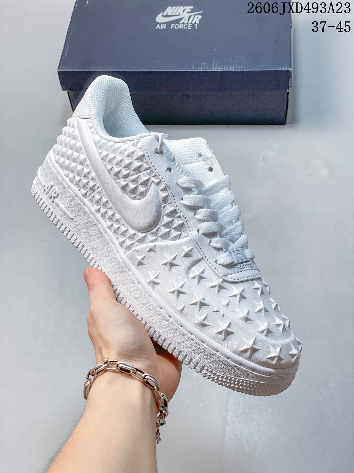 Angled side view of the white sneaker with star and geometric raised details