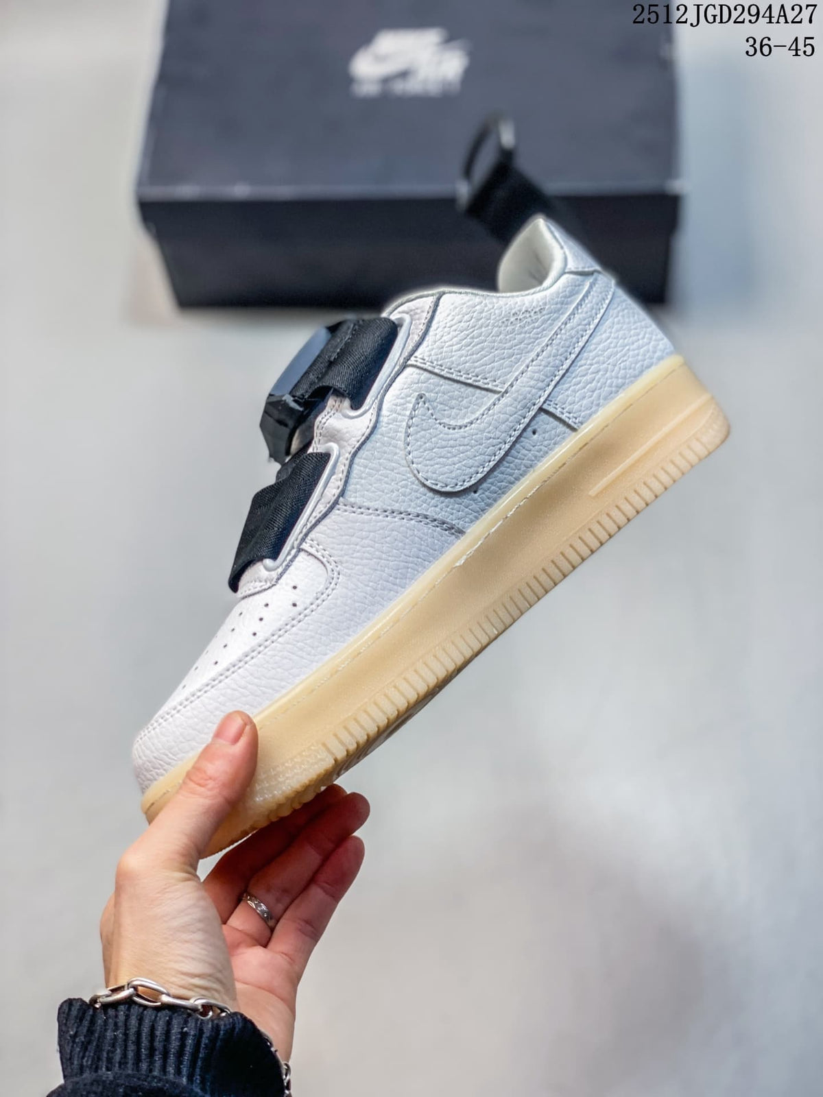 Side view of the white low-top sneaker with black strap and gum-tone sole