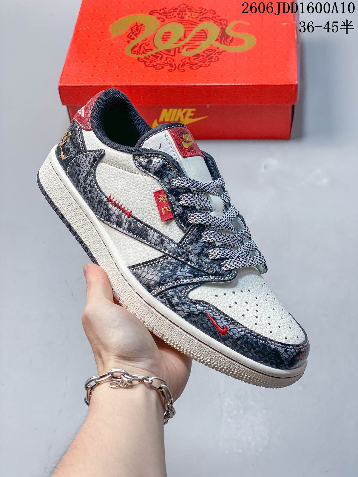 Angled side view highlighting off-white panels, patterned overlays, red details, and contrast laces