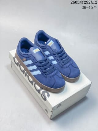 Pair of blue Adidas low-top sneakers with white side stripes on a shoebox.