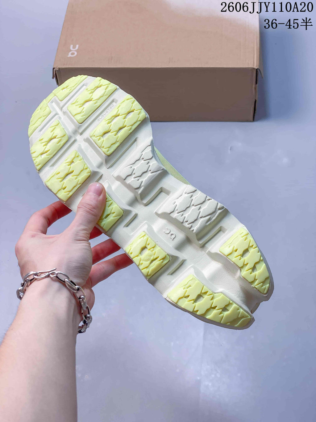 Underside of the pale yellow running shoe showing its segmented tread