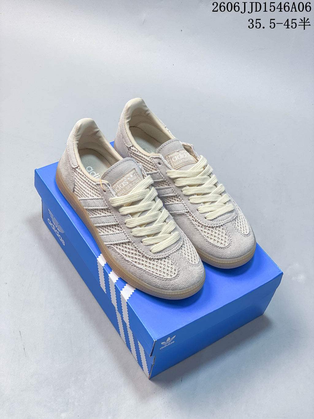 Pair of light grey and cream Adidas Samba low-top sneakers on a blue box