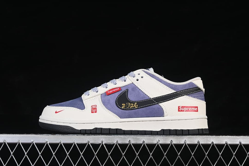 Side view of a blue, white, and black low-top sneaker with red Supreme-branded details.