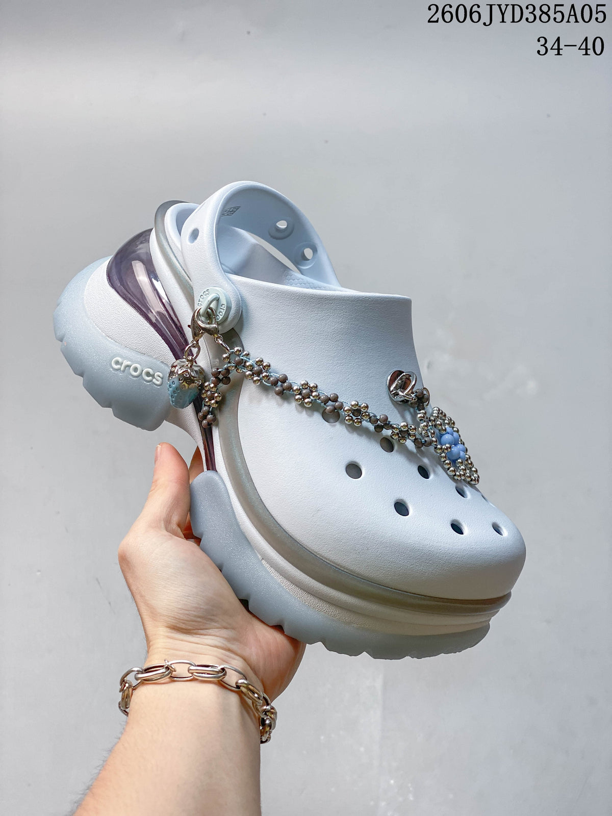 Angled close-up of a white platform clog showing its charms, ventilation holes, and heel strap.