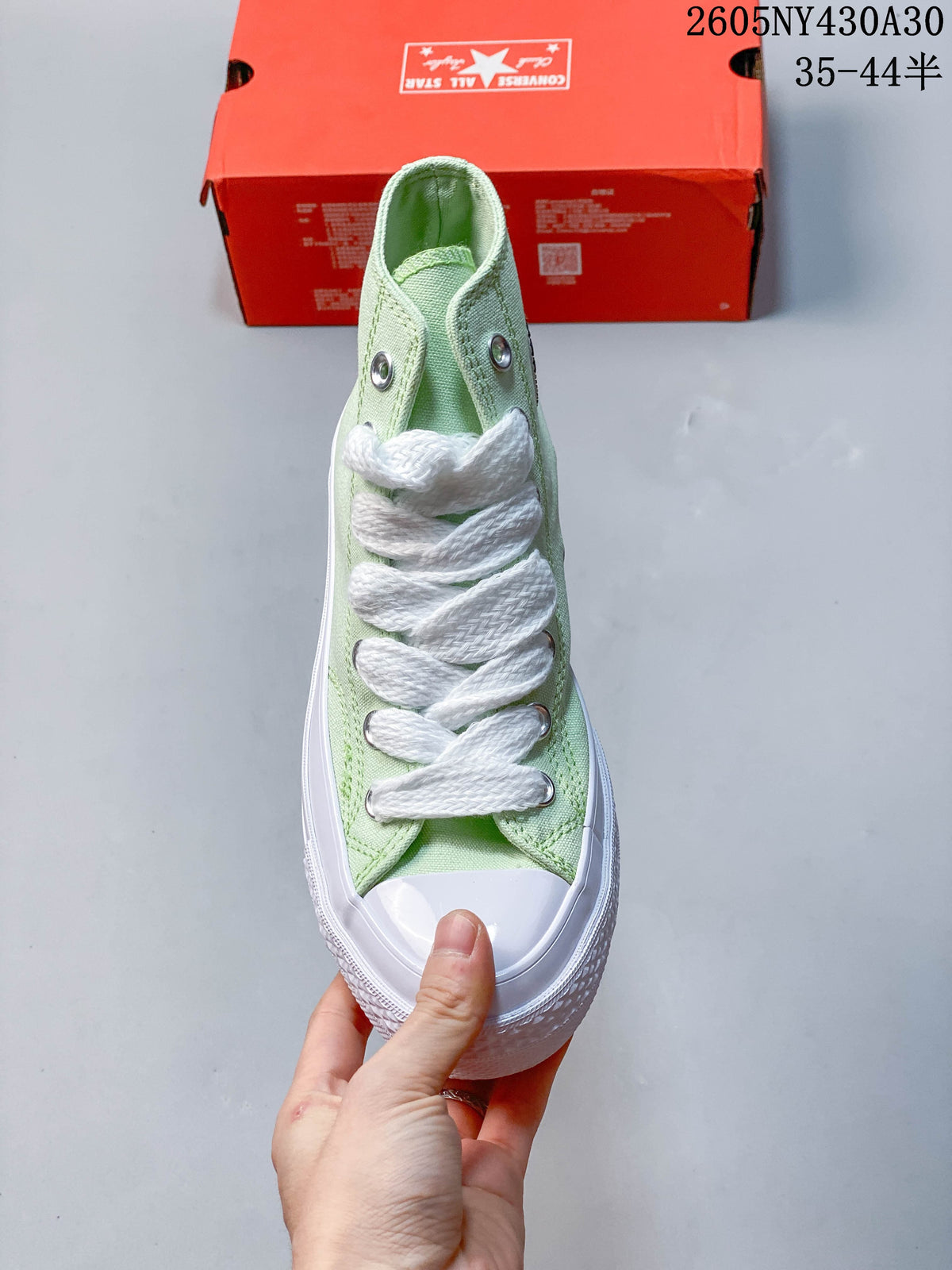 Front view of a mint green high-top sneaker with white laces and a rubber toe cap