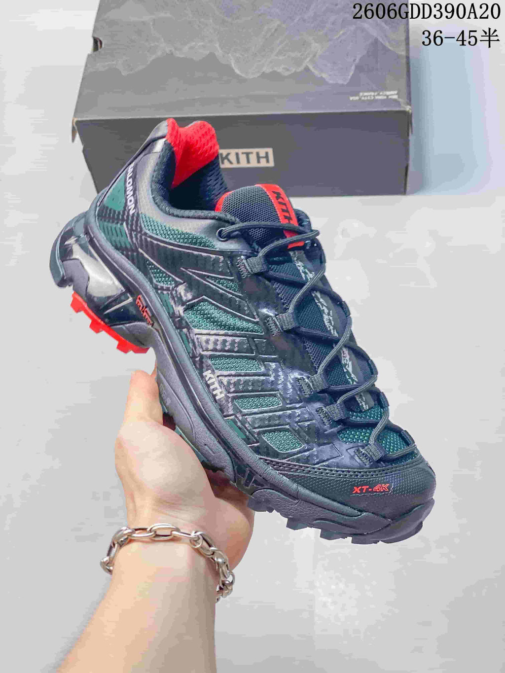 Angled view of a Salomon XT-4K shoe with Kith branding, dark navy and teal panels, and a red-accented lugged outsole.