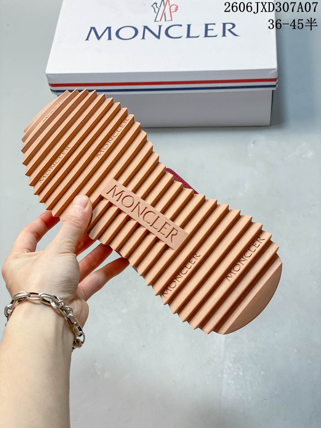 Close-up of the sneaker's deeply ridged tan outsole beside a branded box.
