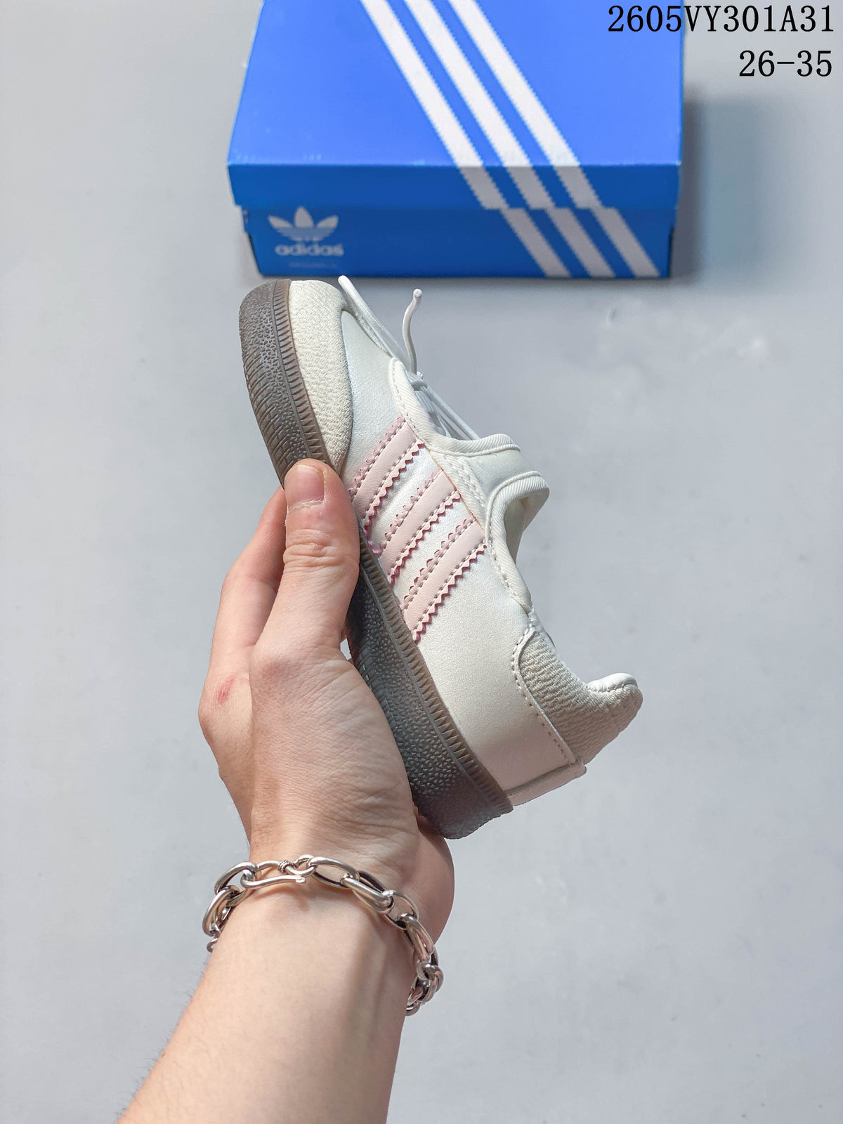 Side profile of a cream Samba Jane kids' shoe with pink stripes, laces, an instep strap, and brown outsole.