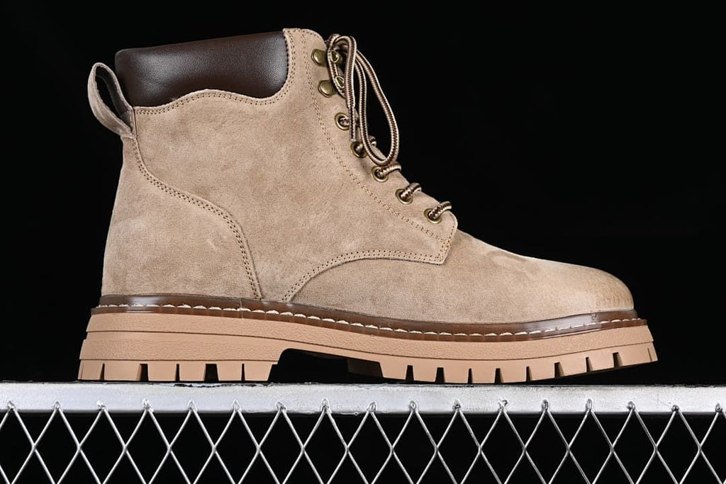 Side profile of a khaki mid-top lace-up boot with a dark padded collar and lugged outsole.