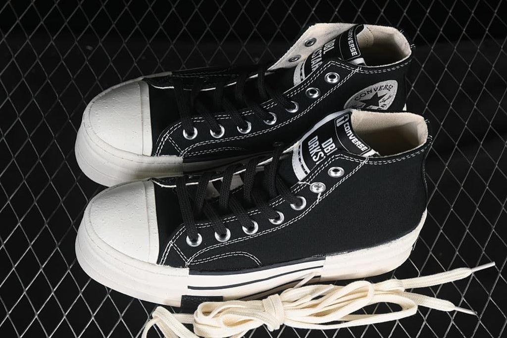 Pair of black high-top sneakers with thick white soles and spare light-colored laces