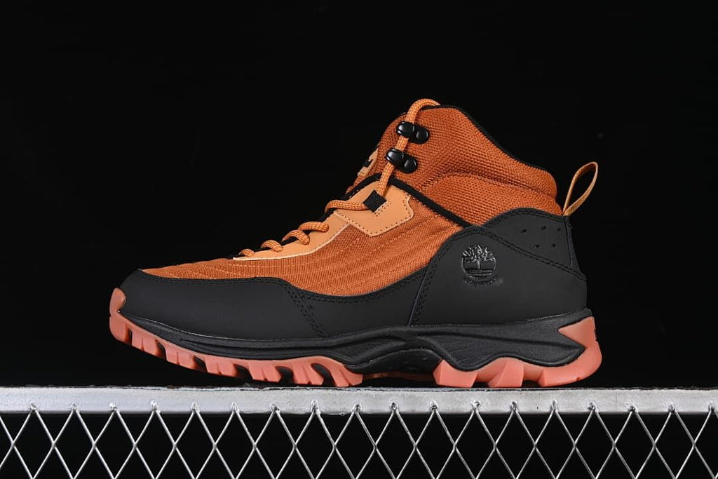 Side profile of an orange and black Timberland mid hiking boot