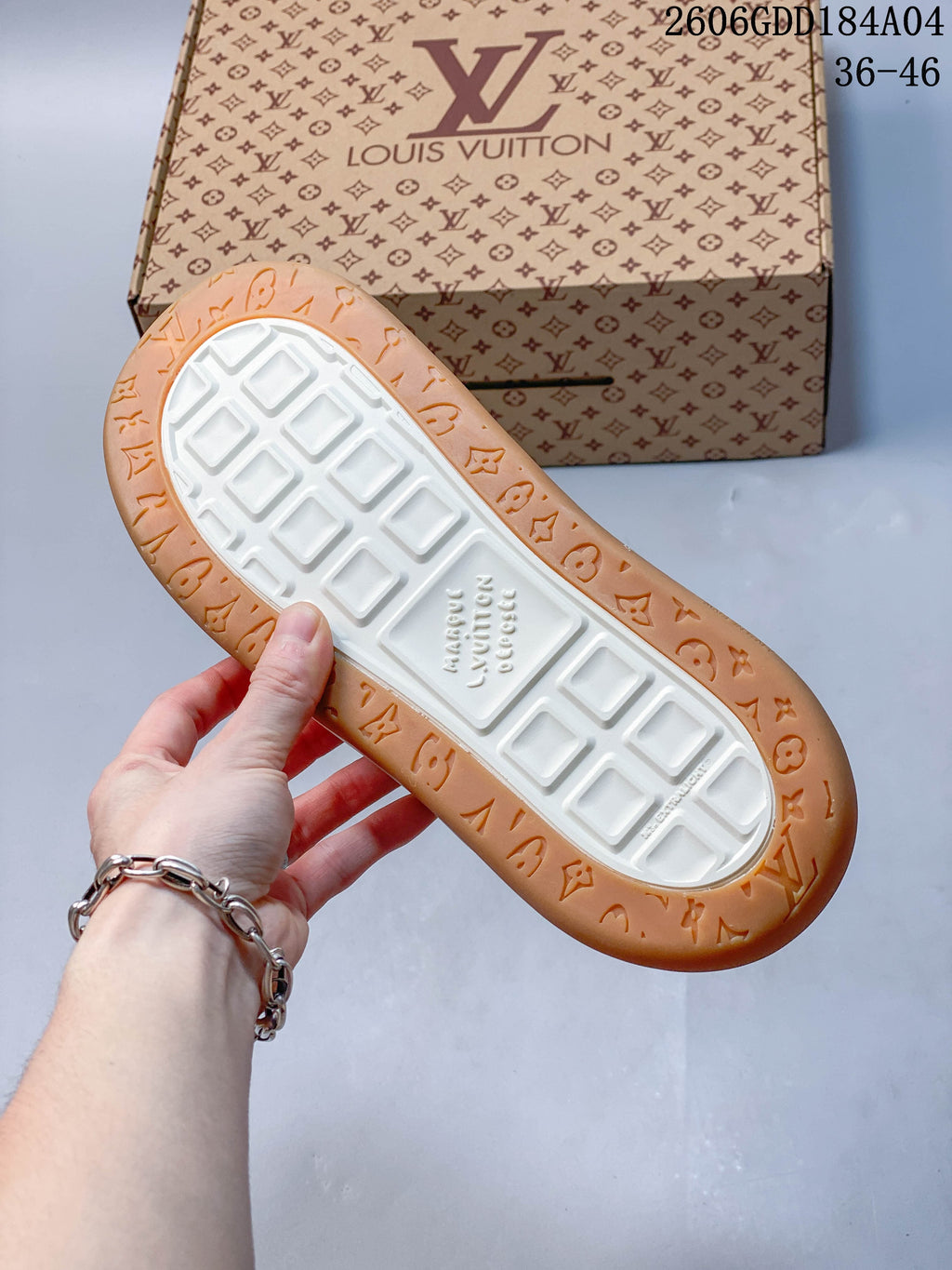 Underside of a sneaker showing a white tread center and tan patterned outer sole