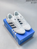 Pair of white Adidas Originals Taekwondo low-top sneakers with dark stripes and laces on a blue shoe box