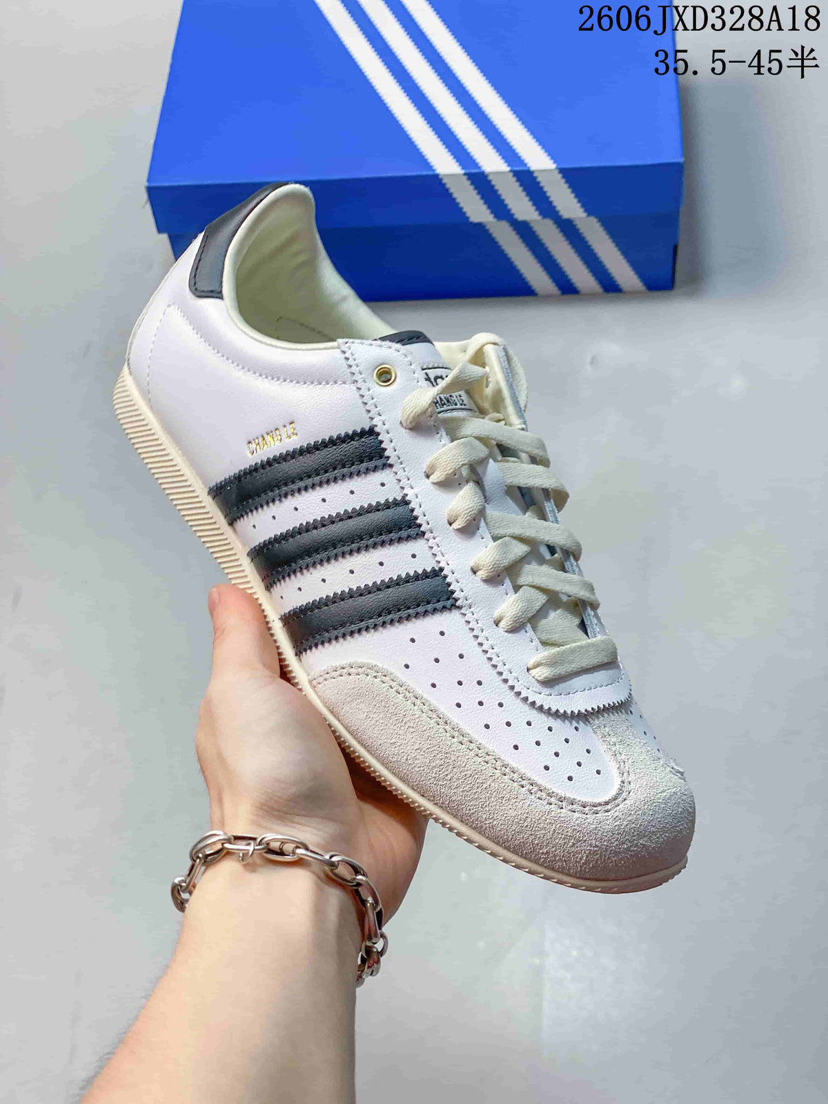 Close side view of the white sneaker with dark stripes and a textured toe overlay