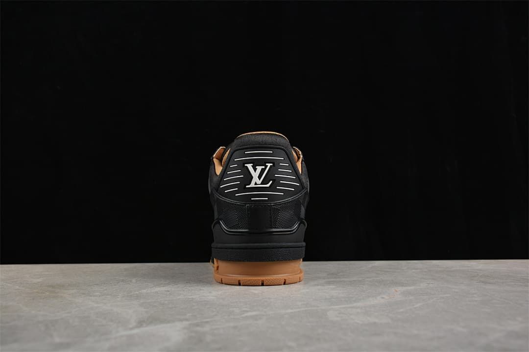 Rear view of a black sneaker with logo detailing and a tan-colored outsole
