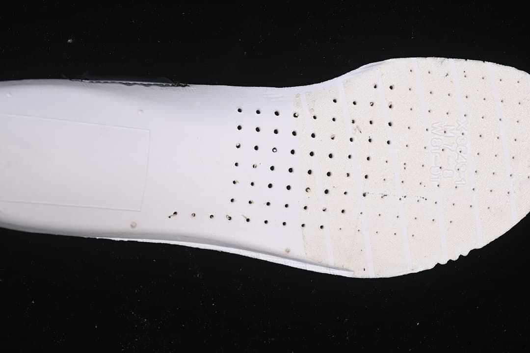 Close-up of the shoe outsole showing its light-colored surface and traction details.