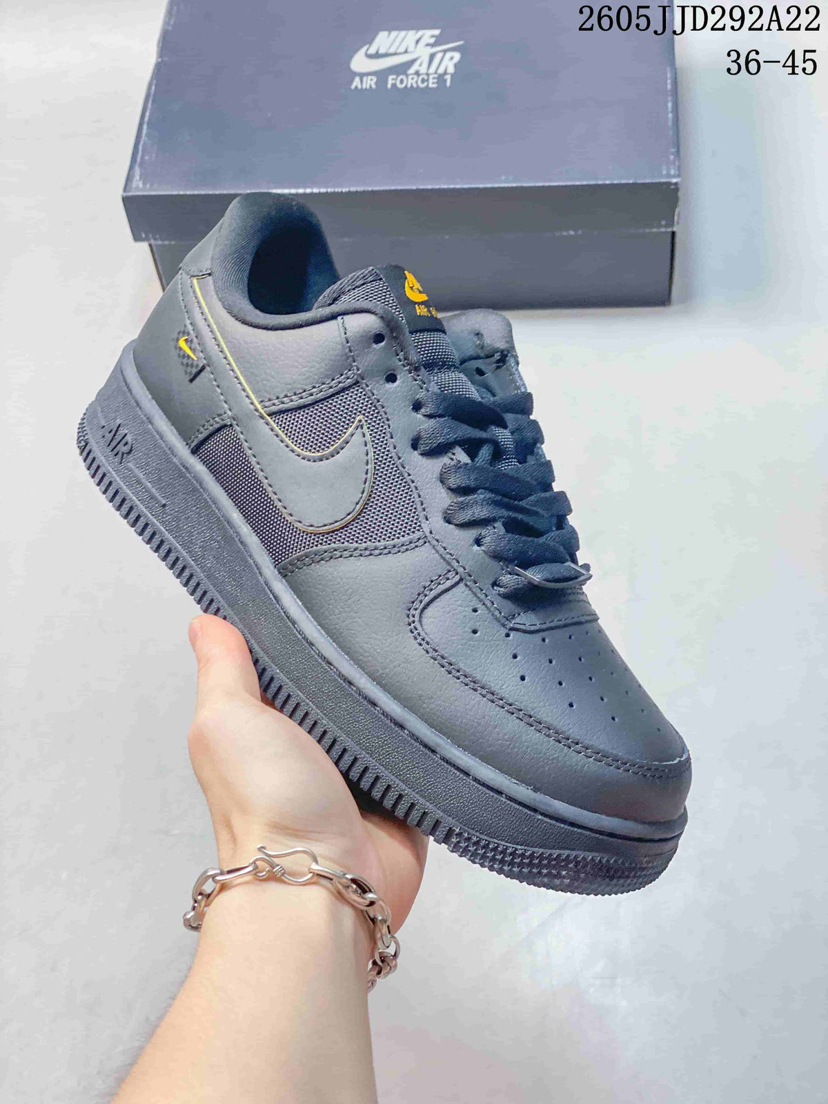 Dark gray low-top sneaker with mesh-look side panels and yellow accents.