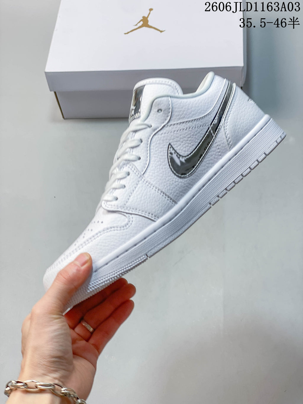 Side view of a white Jordan Air Jordan 1 SE low-top sneaker with a reflective silver-tone logo.