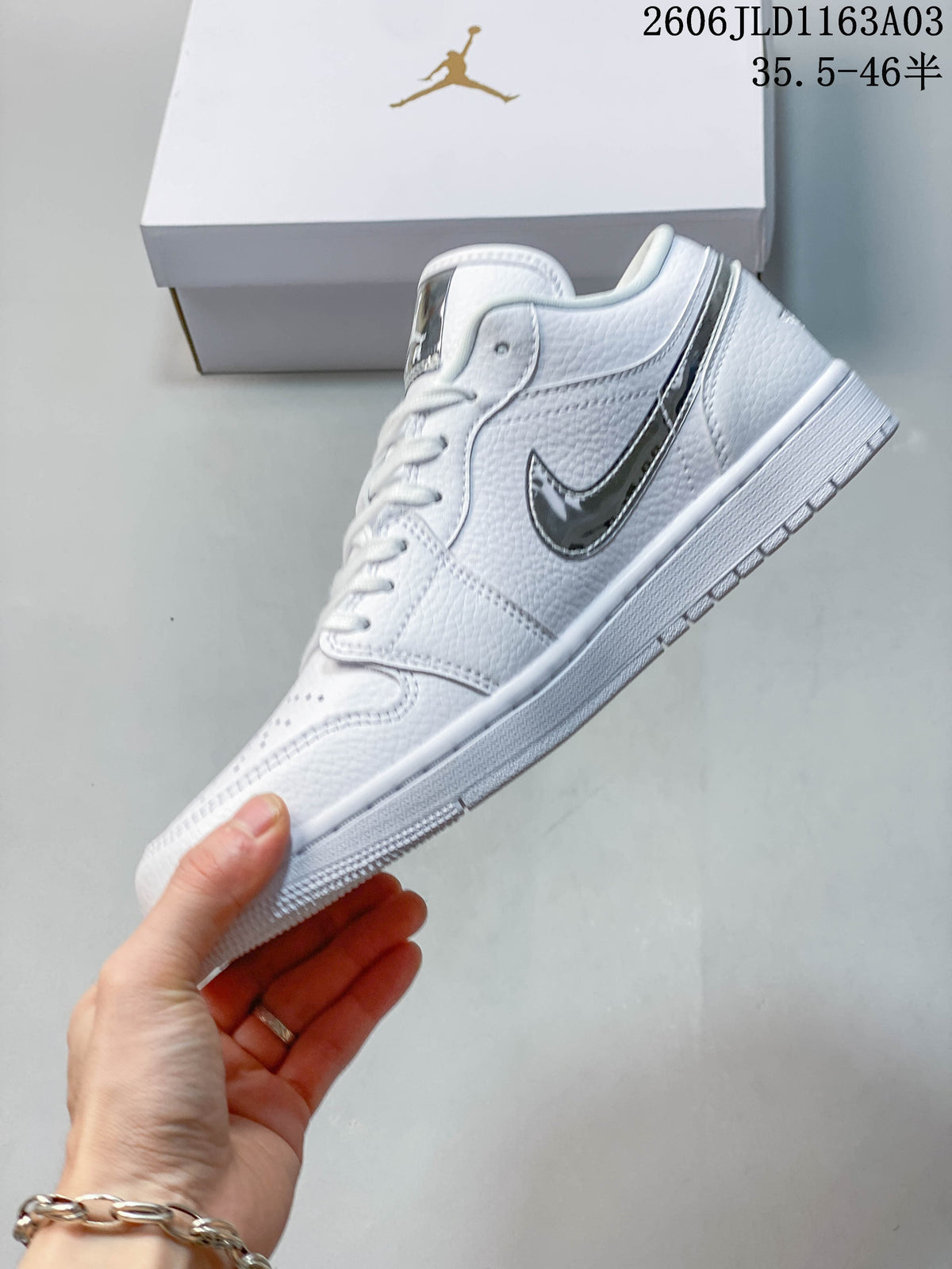 Side view of a white Jordan Air Jordan 1 SE low-top sneaker with a reflective silver-tone logo.