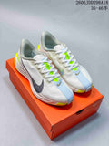 Pair of light-colored Nike Pegasus Plus running shoes with pale blue and bright volt details, shown on an orange shoe box