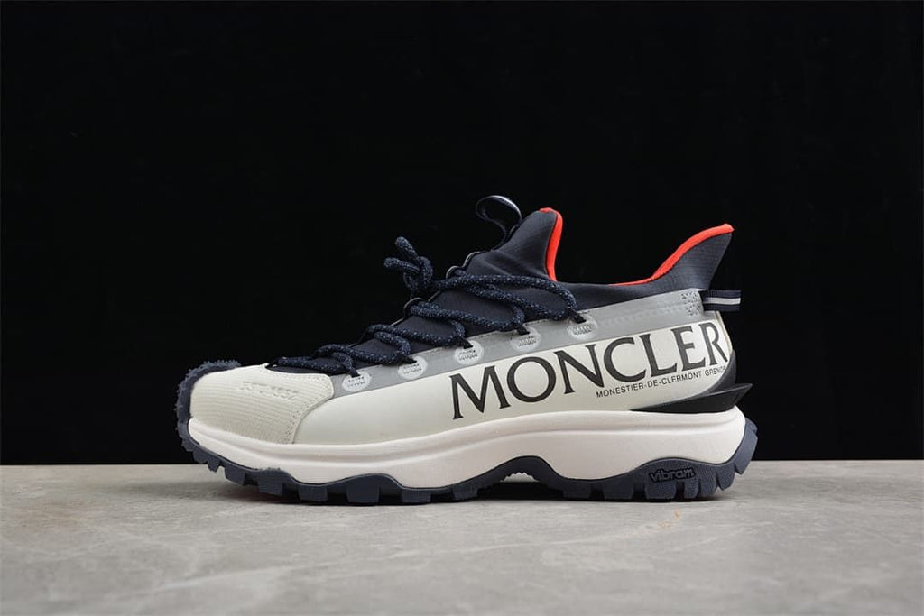 Side view of a white and navy Moncler Trailgrip Lite2 sneaker with red accents.