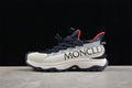 Side view of a white and navy Moncler Trailgrip Lite2 sneaker with red accents.