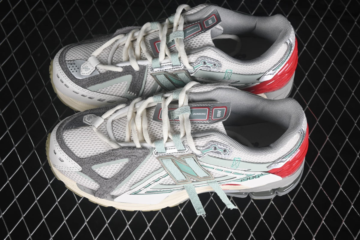 Pair of New Balance 1906 sneakers shown from an angled top view in white, grey, mint and red.